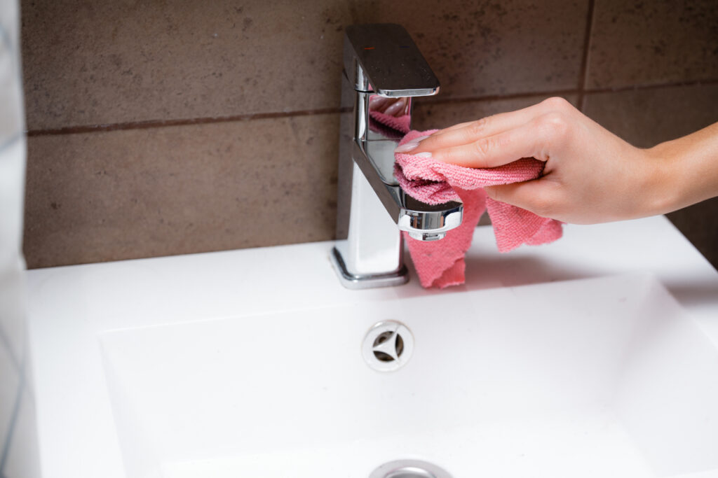 A woman's hand cleaning the bathroom sink