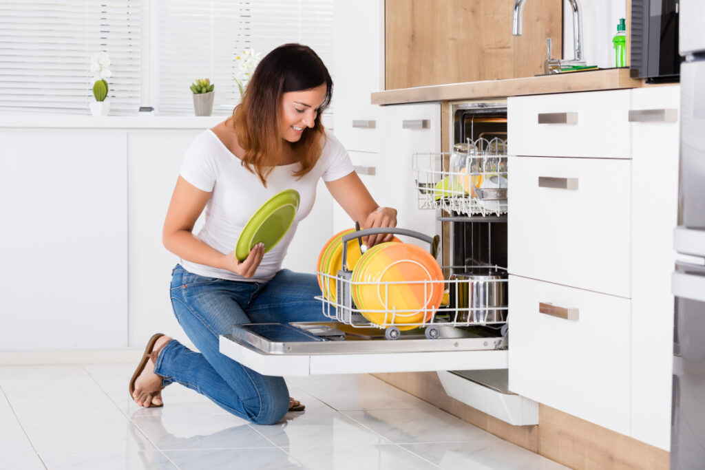 Woman Arranging Plates In Dishwasher